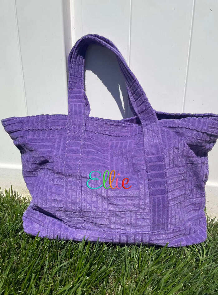 Purple terry cloth beach tote bag from Travellers Hat Boutique with textured pattern and dual handles