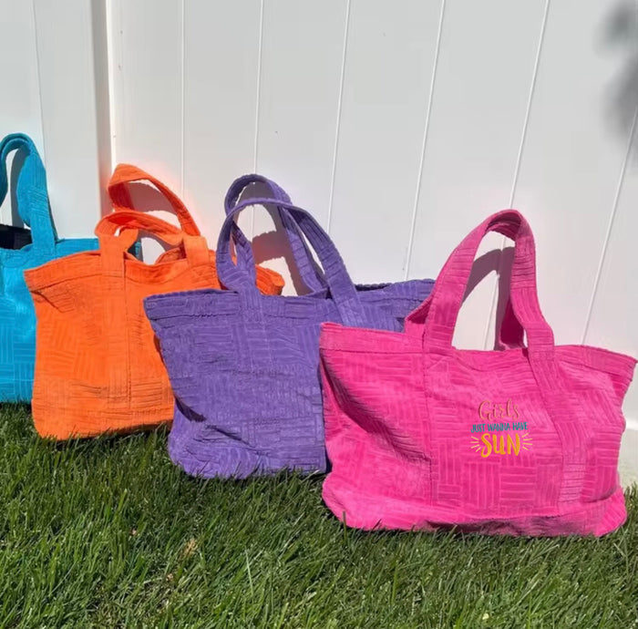 Colorful terry cloth beach tote bags in blue orange purple and pink with sun graphic