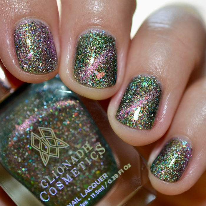 Close-up of nails painted with Th1rt3en Nail Lacquer on fair skin tone. Hand is holding polish bottle.