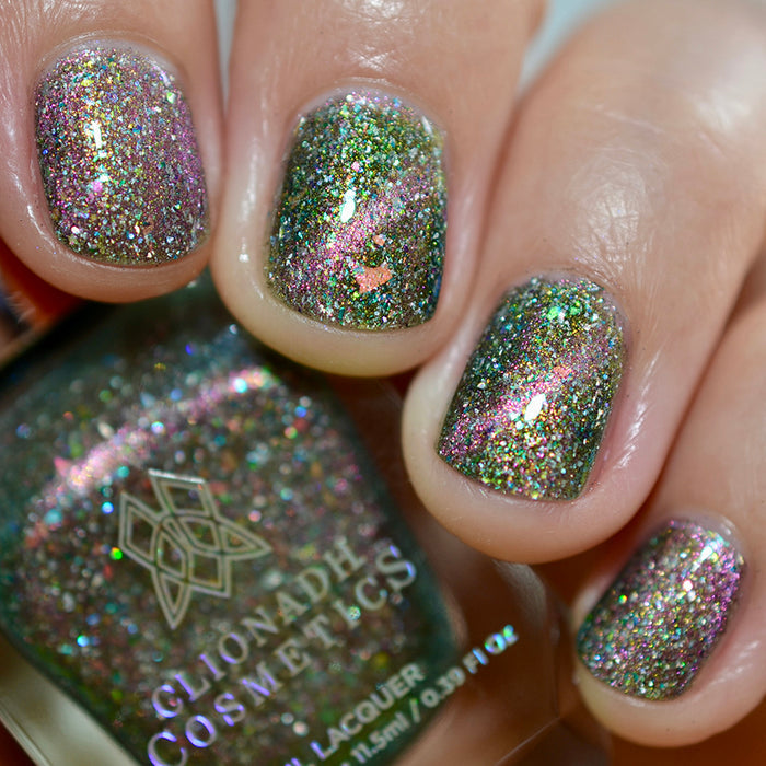 Close-up of nails painted with Th1rt3en Nail Lacquer on fair skin tone. Hand is holding polish bottle.