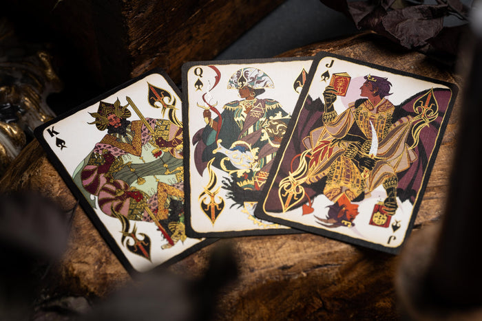 Three playing cards with intricate designs on a wooden surface