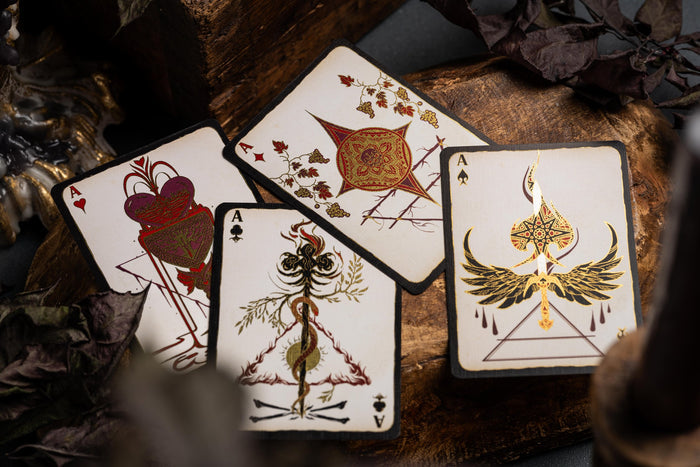 Four playing cards with intricate designs on a wooden surface.