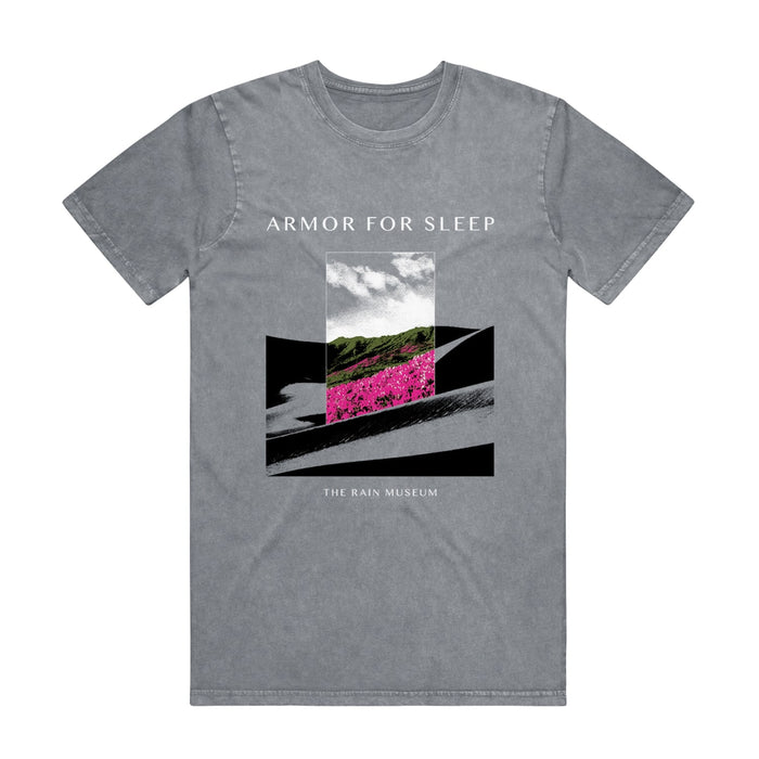 Ash stone colored short sleeve shirt with ARMOR FOR SLEEP written in white text above an image. Below the image there is smaller white text that says THE RAIN MUSEUM. The artwork is black and white hills with a rectangle in the center with hills and pink flowers in the center.