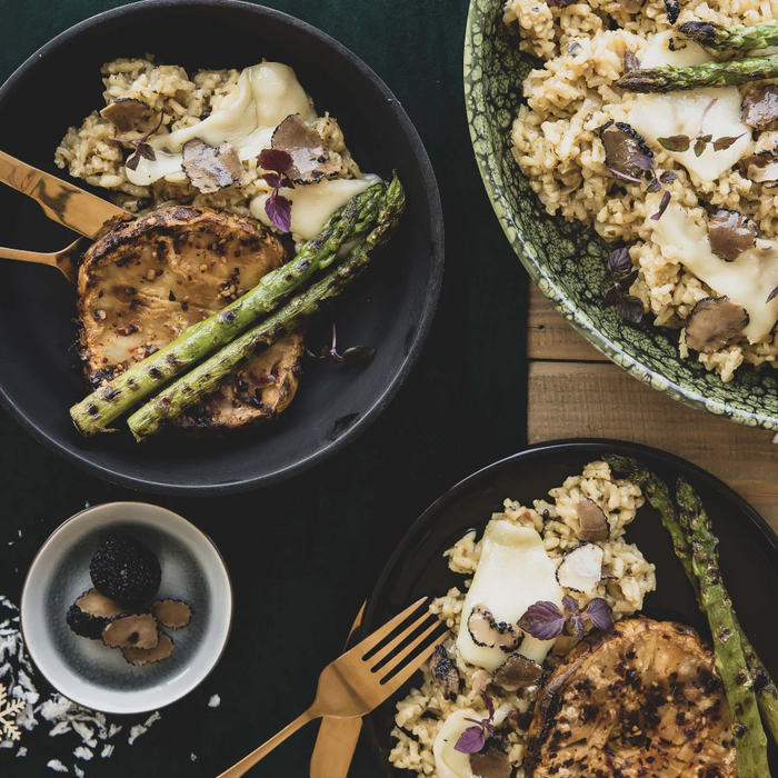 plate of risotto with truffles and asparagus on a black tablescape