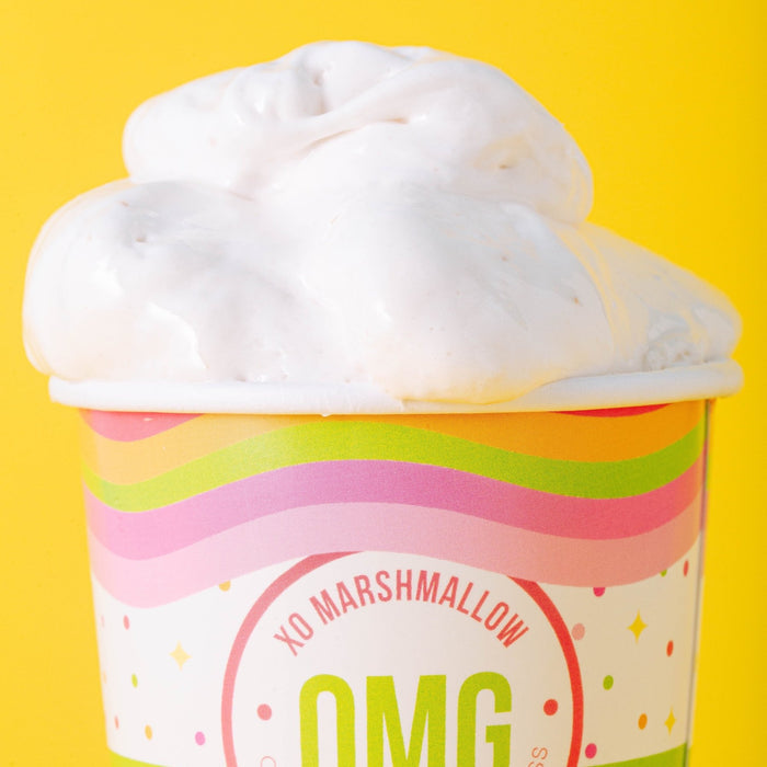 A zoomed in cropped photo of a cloud of vegan marshmallow creme spilling out of it's ice cream pint container with a bright yellow background.