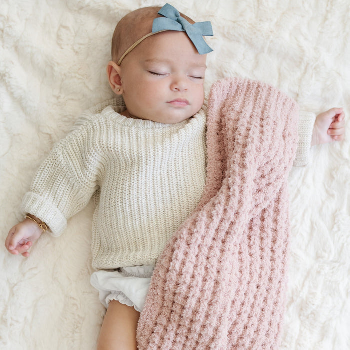 Baby girl sleeping with pink waffle knit mini blanket.