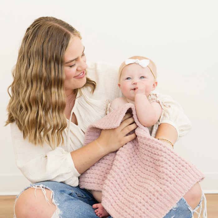 Mom holding baby girl, snuggled with a Rosette Waffle Knit mini baby blanket.