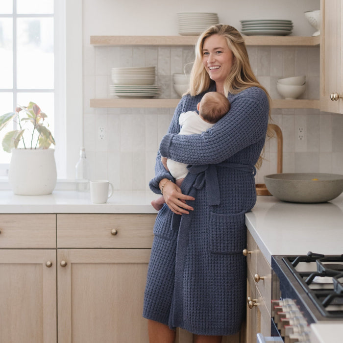 Mother holding baby at home while wearing blue waffle knit robe.