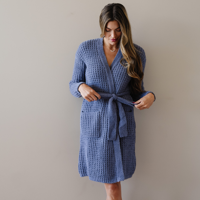 Woman stands wearing an oxford blue waffle knit robe.