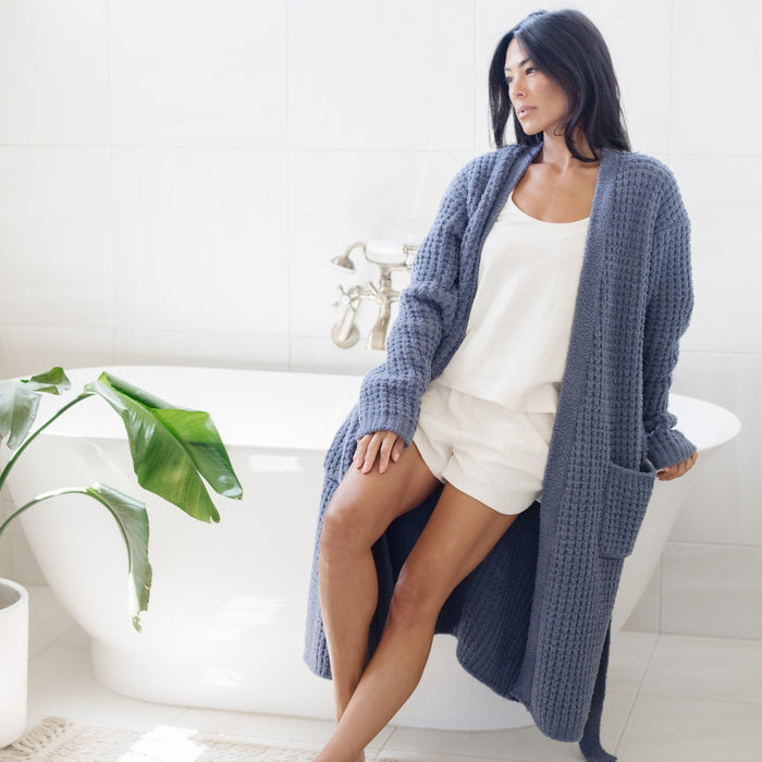 Woman in luxurious bathroom wearing cozy, blue waffle knit robe.