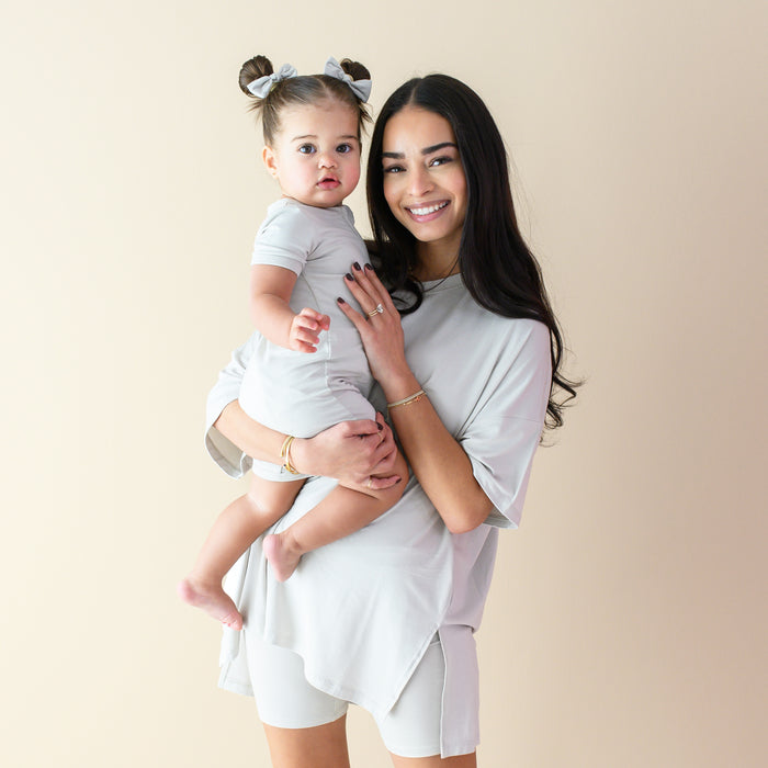 Mom wearing Women’s Biker Short Set in Oat holding baby wearing Zippered Shortall in Oat
