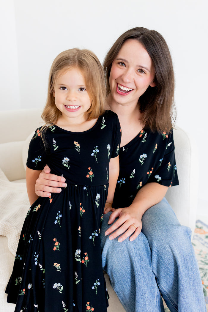 Girl standing in Twirl Dress in Midnight Wildflower print with a model wearing Women's Relaxed Fit V-Neck in similar print over blue jeans