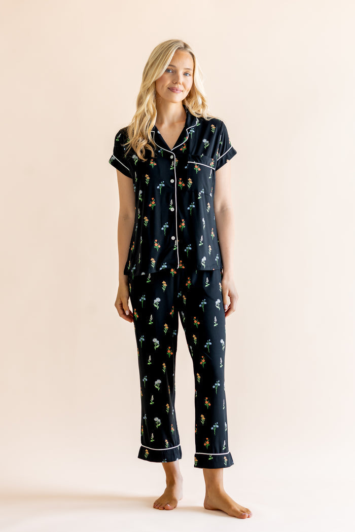 Model wearing Women's Short Sleeve Cropped Pajama Set in Midnight Wildflower print on a beige background