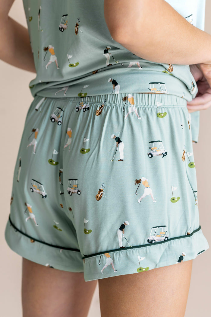 Model showing the back of Women's Short Sleeve Pajama Set shorts in Golf print on beige background