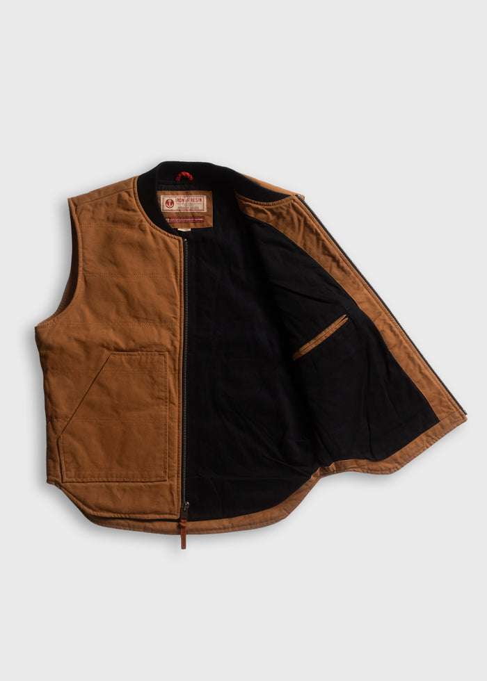 Brown vest with black lining, open to show interior pocket and label. Simple, rugged design on a plain background.