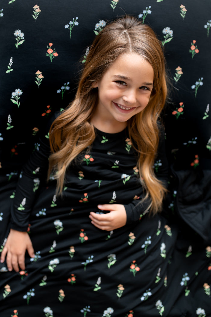 Girl lying on Standard Pillowcase in Midnight Wildflower print over a similar print sheets and youth blanket