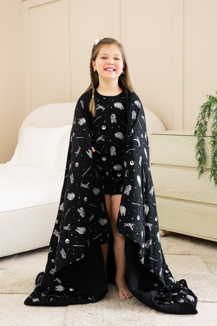Girl standing with Youth Blanket in STAR WARS™ 2.5 print wearing similar print short sleeve pajama set