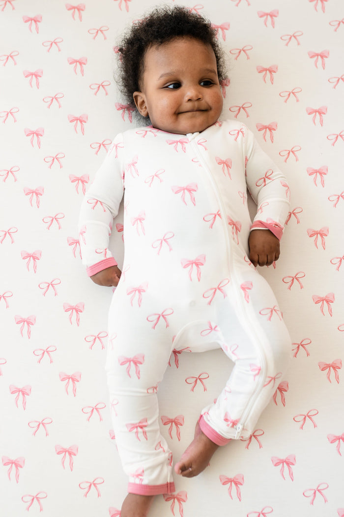 Baby wearing Zippered Romper in Bow in crib