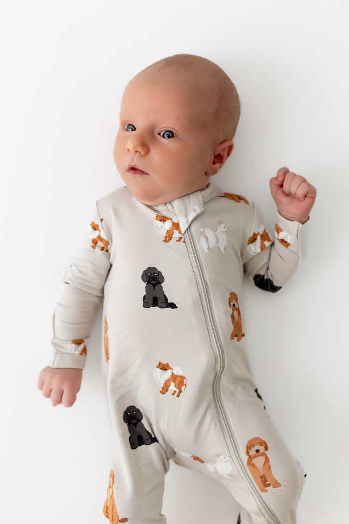 Baby wearing a dog patterned onesie with animals on a white background