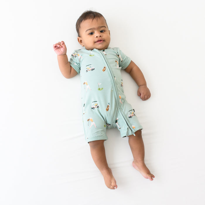 Infant wearing Kyte Baby Zippered Shortall Romper with dual zipper in Golf